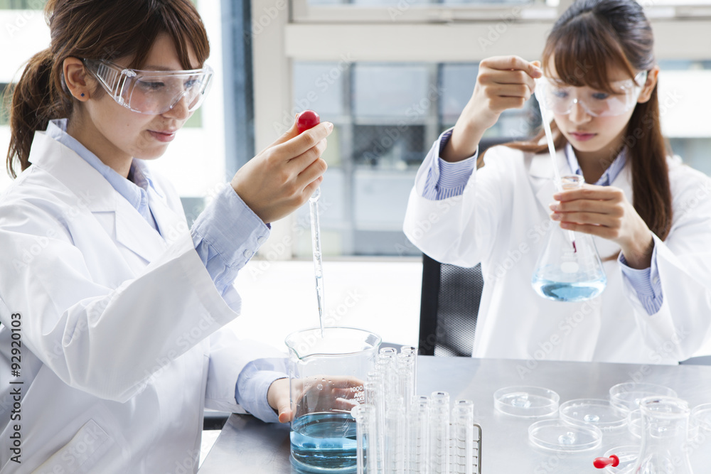 The women are experimenting with wearing a white coat and goggles The women are experimenting with wearing a white coat and goggles