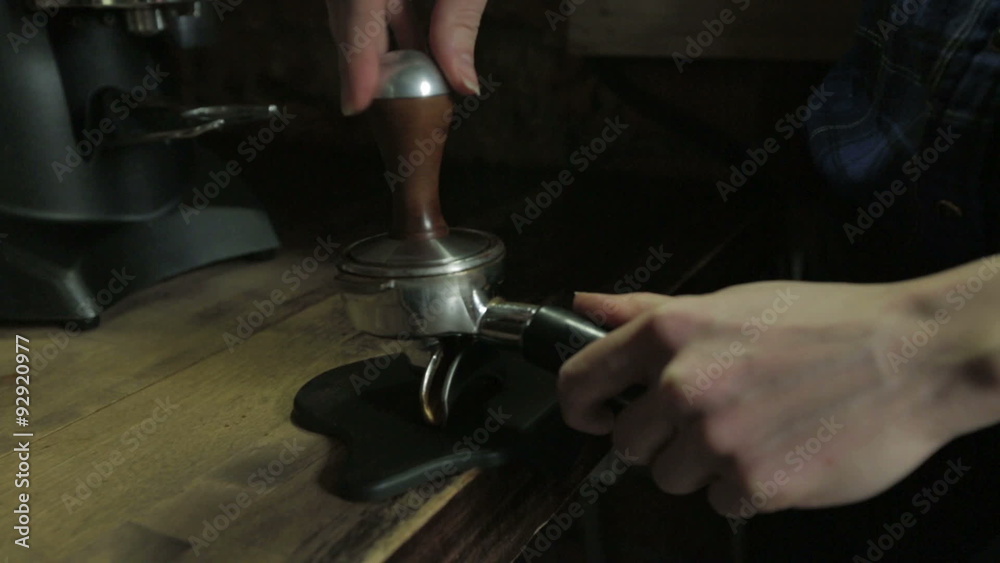 Barista tamping the grind coffee for espresso, close-up Barista tamping the grind coffee for espresso, close-up