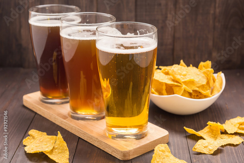 Assortment of beer glasses with nachos chips  on a wooden table