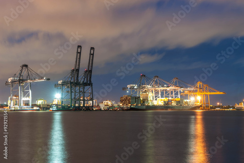 Container Cargo freight ship with working crane bridge in shipyard at dusk for Logistic Import Export background. Containers loading by big crane during twilight, Shipping Trade Port in Thailand