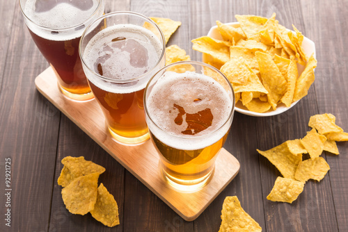 Assortment of beer glasses with nachos chips  on a wooden table