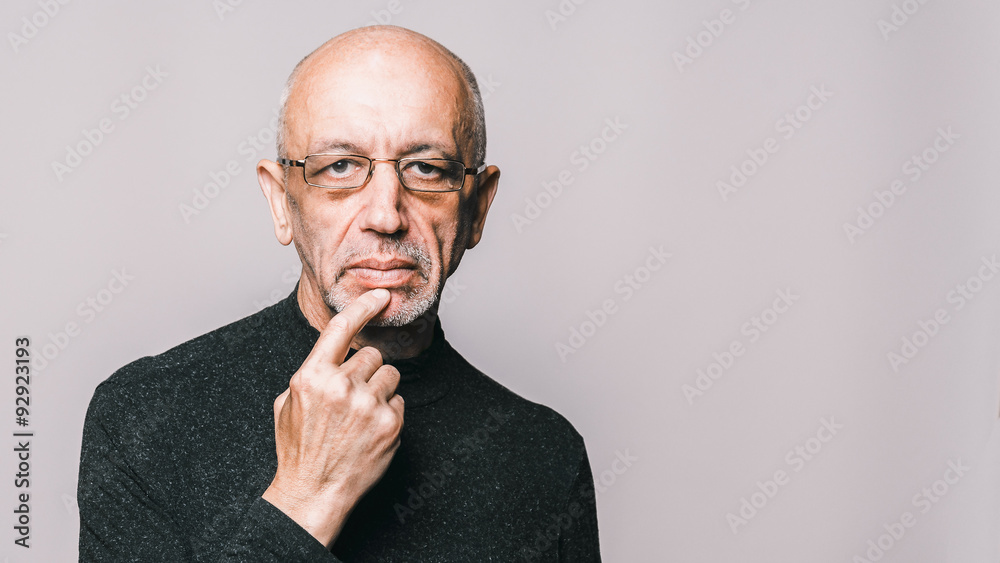 Thoughtful elderly man with glasses on gray background with copy Thoughtful elderly man with glasses on gray background with copy