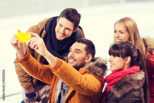 happy friends with smartphone on skating rink