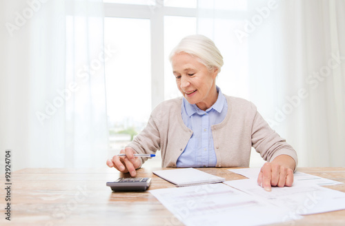 senior woman with papers and calculator at home
