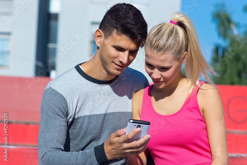 attractive couple with smartphone outside