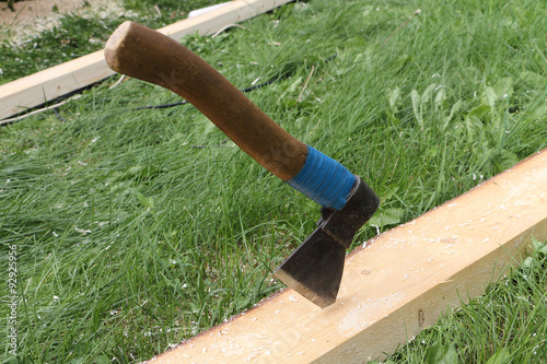 Axe in a pine board against a grass outdoors