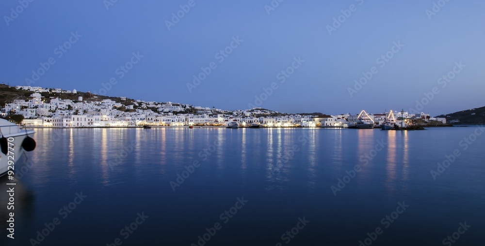 Night view of Chora and the port in Mykonos,Greece.Hora town cityscape lights reflected on the sea,whitewashed greek island houses in the harbour and yachts anchored.A colourful and beautiful seascape