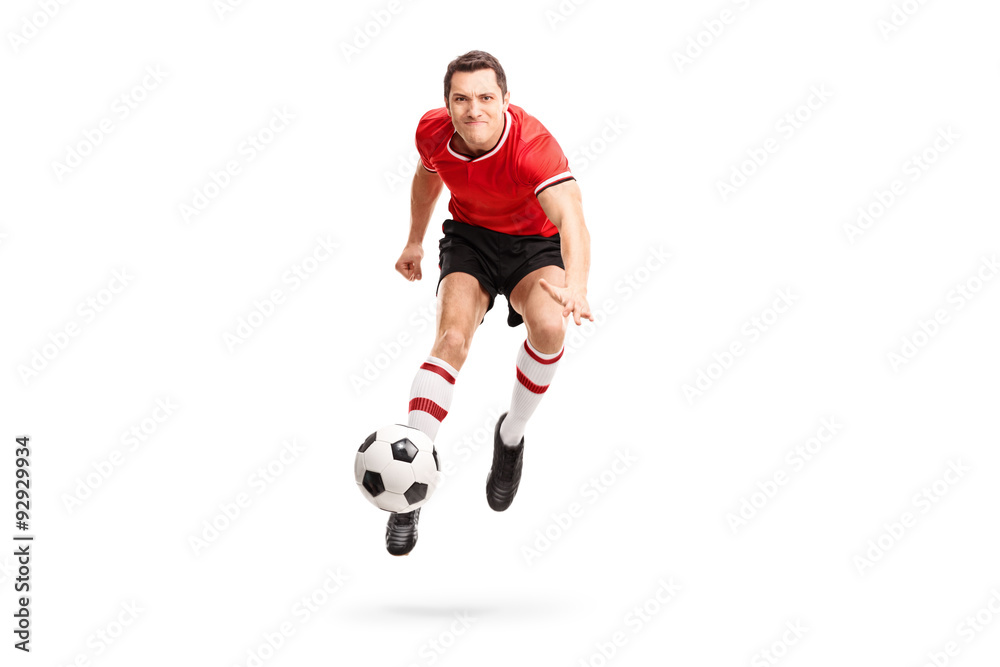 Young sportsman kicking a football in mid-air