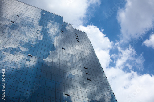 Abstract glass building reflecting clouds and blue sky