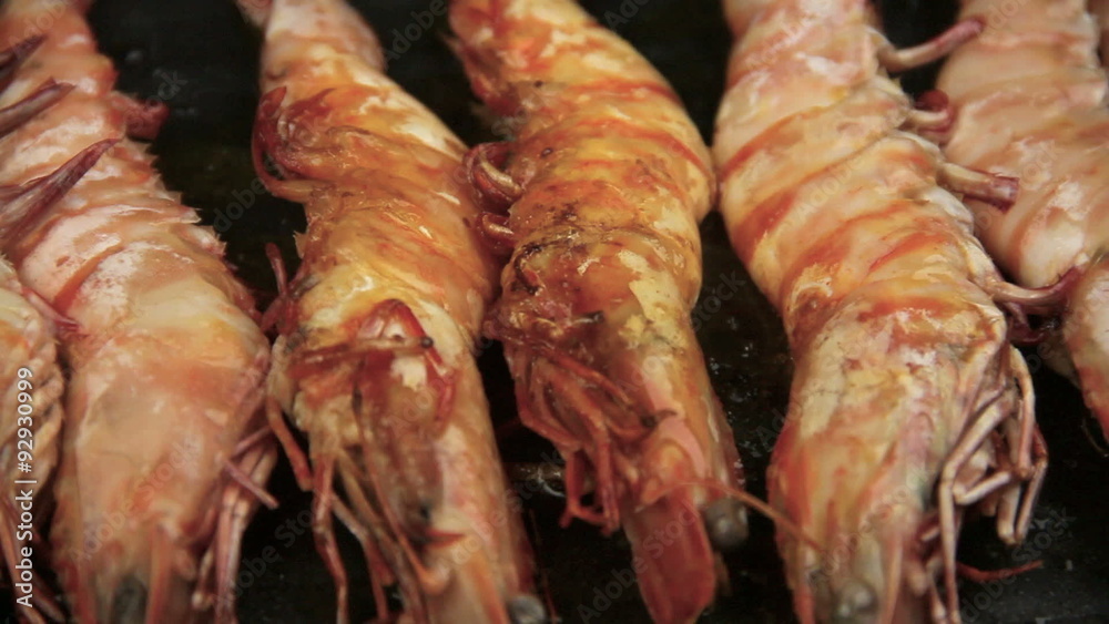 Close up of single whole shrimps on skewers being turned in a griddle fry pan. Close up of single whole shrimps on skewers being turned in a griddle fry pan.