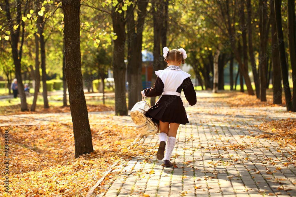 Fototapeta premium Happy little schoolgirl go home from school