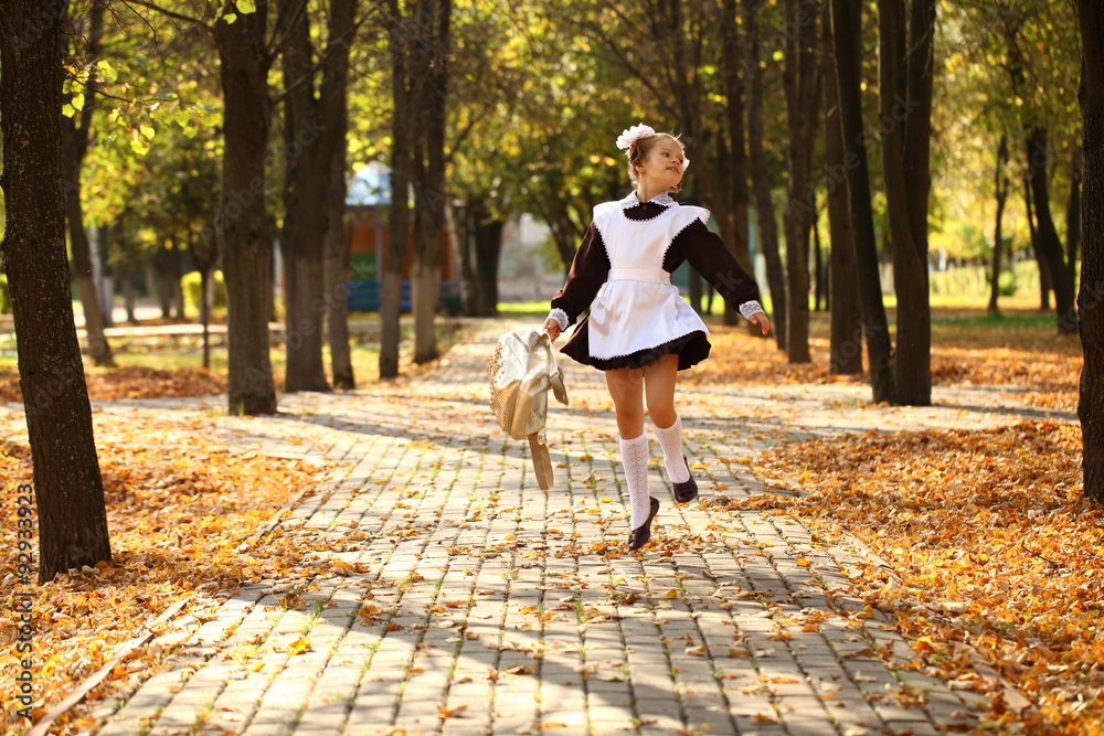 Fototapeta premium Happy little schoolgirl go home from school