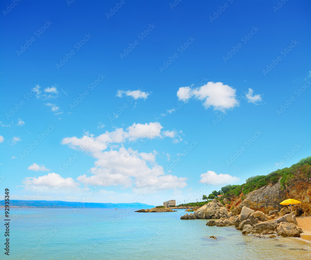 Naklejka premium yellow umbrella by the shore in Alghero