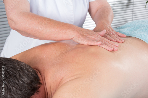 Cheerful young man getting back massage at spa