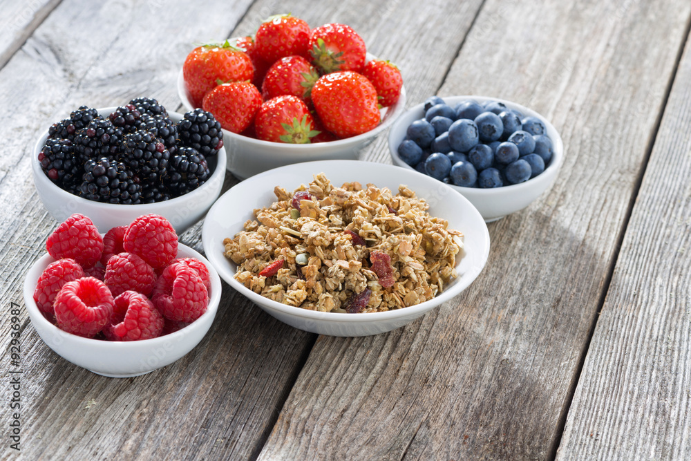 muesli and garden berries on wooden background muesli and garden berries on wooden background