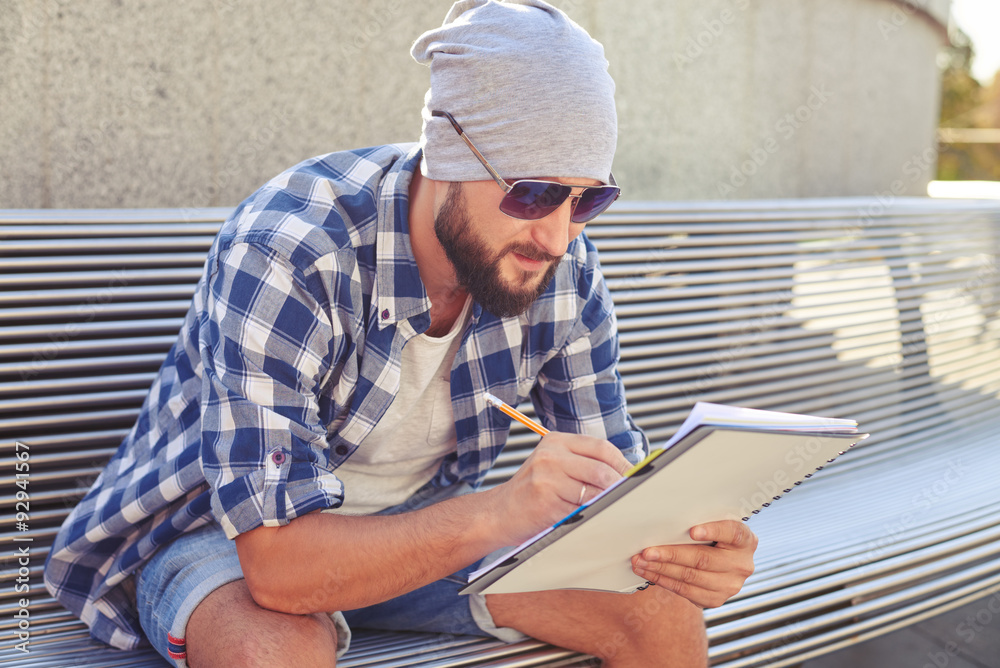 stylish bearded man sitting on bench and writing stylish bearded man sitting on bench and writing
