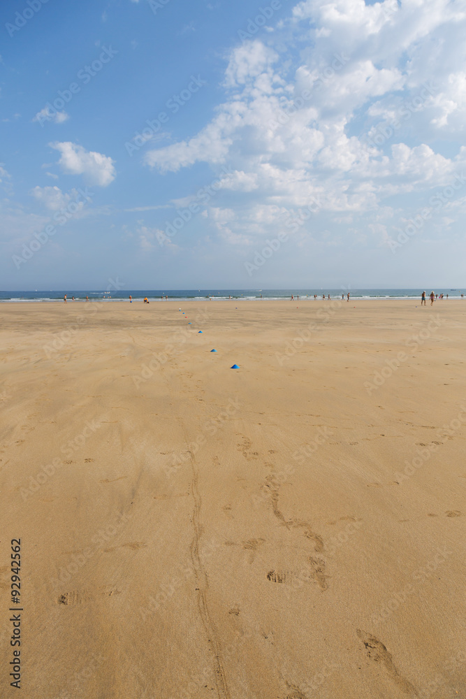 The sandy beach of the Atlantic Ocean. South of France. Basque Country. Hendaye. Blue sky with high clouds and yellow sand. horizon line in the middle. space for inscriptions
