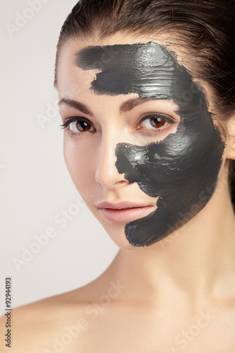 Young woman in mask for face of the black clay