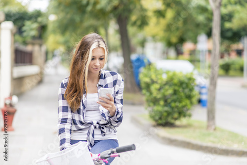 Urban girl with bicycle using phone, adolescence lifestyle concept