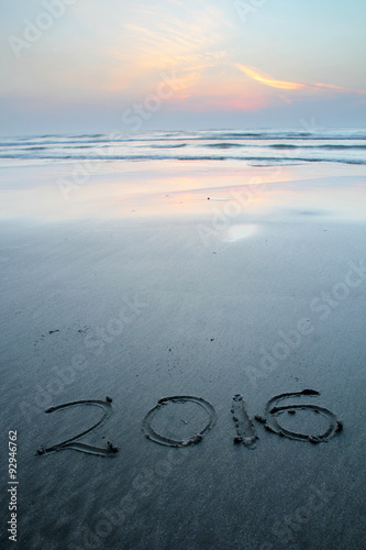 Sandy beach with 2016 written on sand during dawn hours 