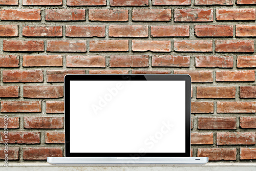 Laptop computer on table with brick wall background.