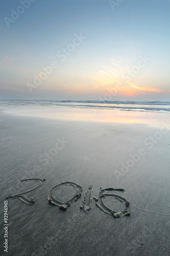 Sandy beach with 2016 written on sand during dawn hours 