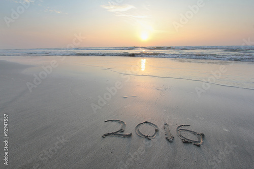 Sandy beach with 2016 written on sand during sunrise