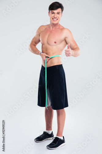 Happy atheltic man measuring his body