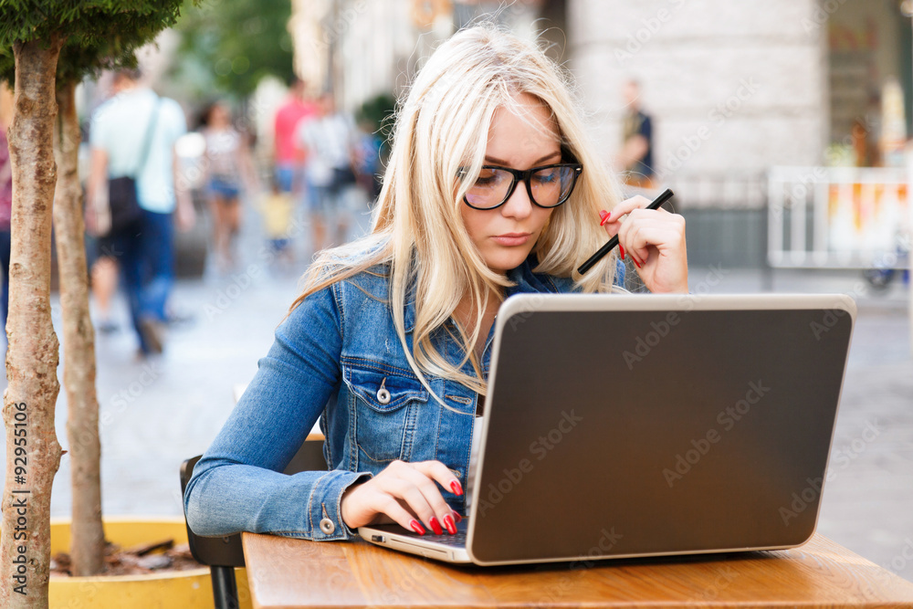 Pretty woman sitting at the table and working with laptop Pretty woman sitting at the table and working with laptop