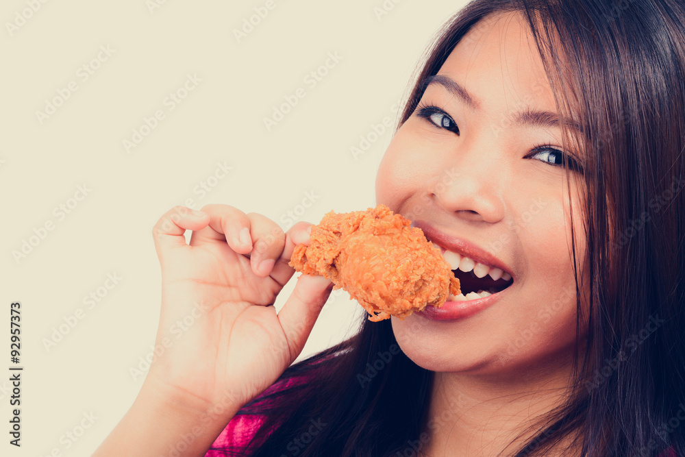 Young woman biting fried chicken, vintage tone