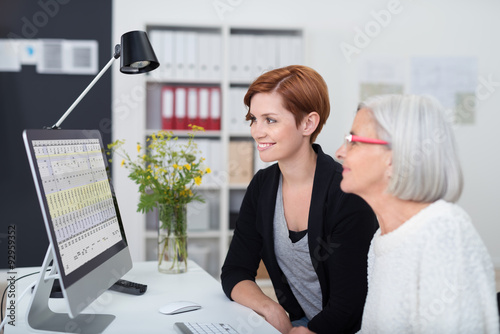 zwei frauen im büro schauen gemeinsam auf den pc photo