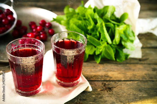 Two glasses with cherry juice on table, on wooden background