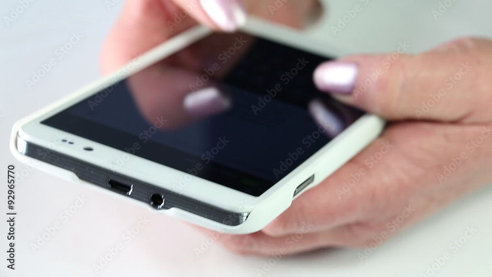 Closeup of woman hands with white smartphone. Woman typing sms on her cell phone Closeup of woman hands with white smartphone. Woman typing sms on her cell phone