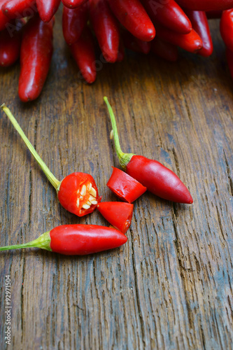 Chilischoten ganz und aufgeschnitten auf Holztisch