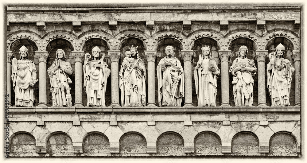 Detail in gable of Our Lady Visitation church, Rochefort, Belgium, Wallonia, antique sculptures of diverse holy persons, monochrome sepia image