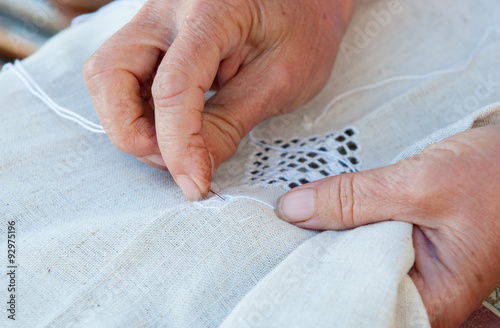 Senior Woman knitting a white fabric cloth photo