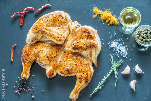Fotografie Grilled chicken with ingredients on the dark wooden background