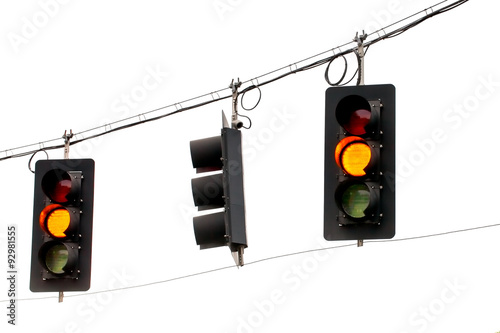 Yellow traffic lights hanging from wires overhead. Isolated against white