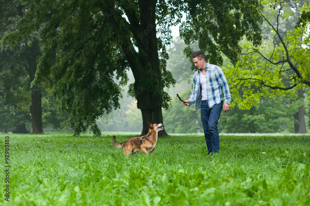 young man playing with his dog and stick