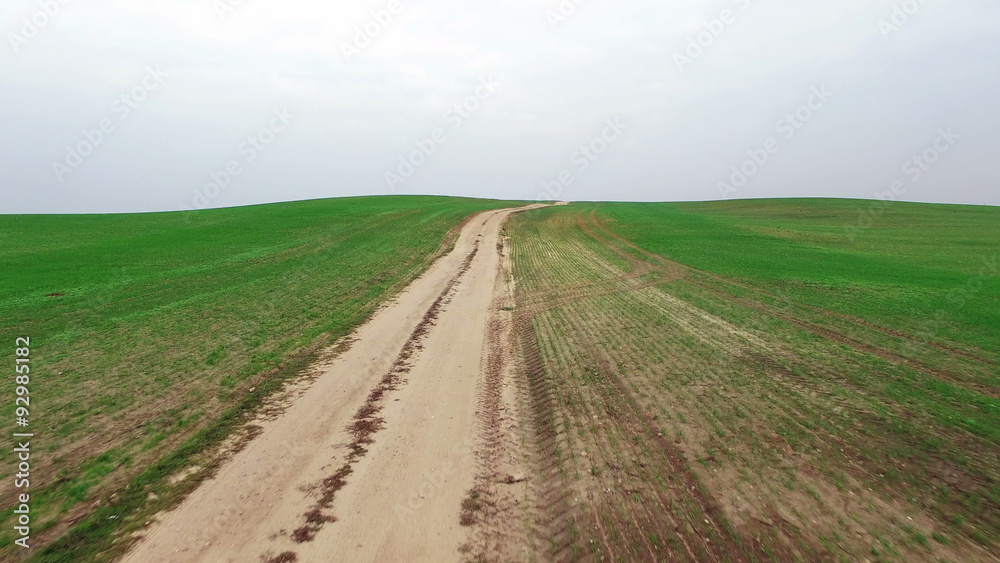 4K. Low flight above green fields with dirt road, aerial panoramic view.
4K. Low flight above green fields with dirt road, aerial panoramic view.