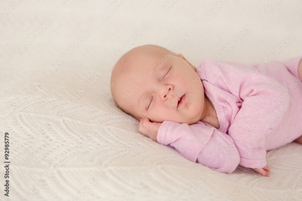 Neugeborenes Baby schläft zufrieden auf weisser Decke