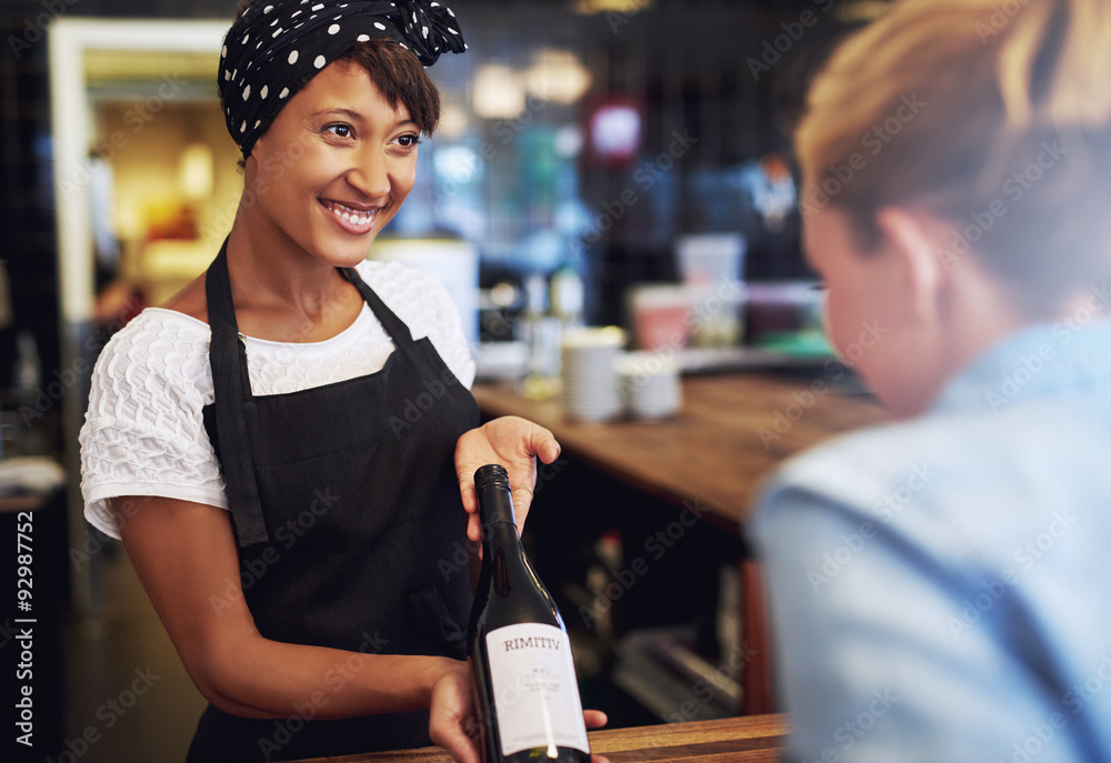 © Flamingo Images - Smiling waitress or bartender showing red wine