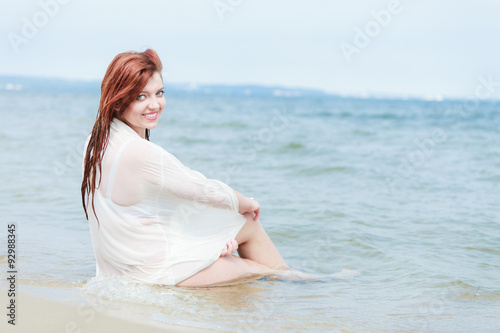 Sensual girl wet cloth in water on the coast.