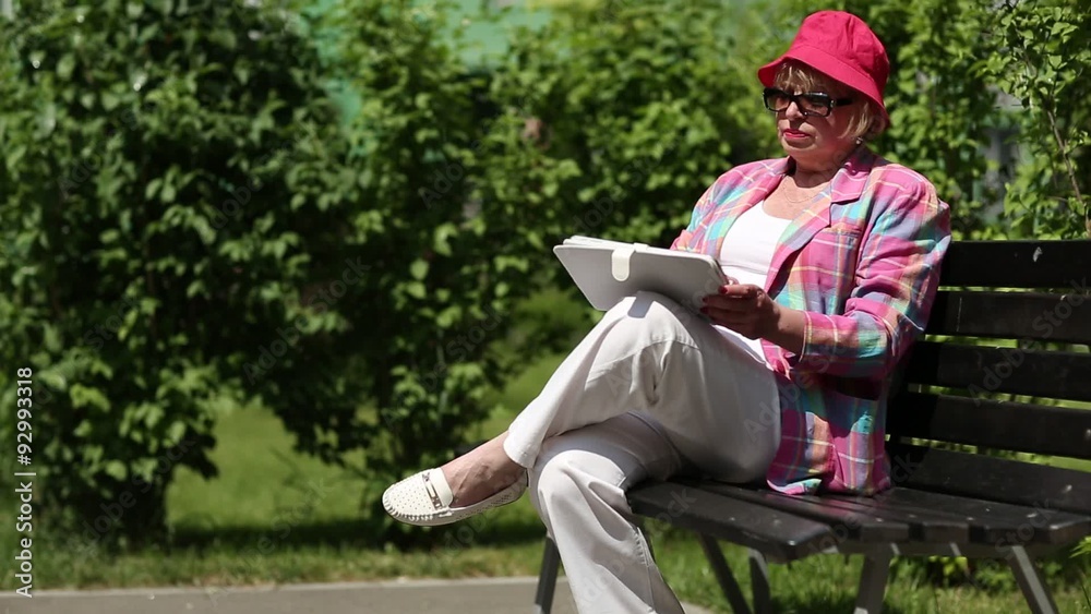Woman sits on the bench and uses tablet computer. Woman with pad Woman sits on the bench and uses tablet computer. Woman with pad