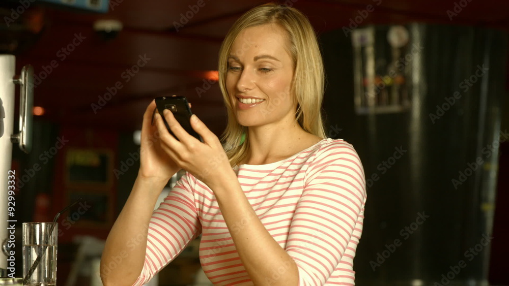 Woman using her phone at the bar Woman using her phone at the bar