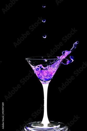 Cocktail glass with splashes on a black background.