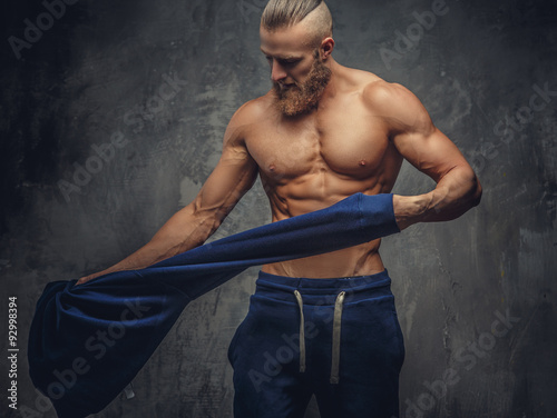 Muscular guy putting out blue sweater.