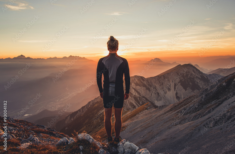 Male hiker observing the sunset at the top of the local big mountain. The photograph was taken in Karavanke mountain range in Slovenia. - obrazy, fototapety, plakaty 