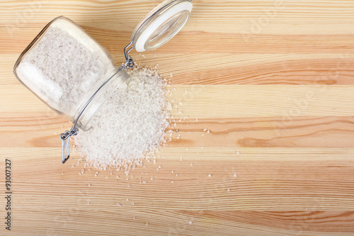 spilling sea salt in glass jar on wooden background