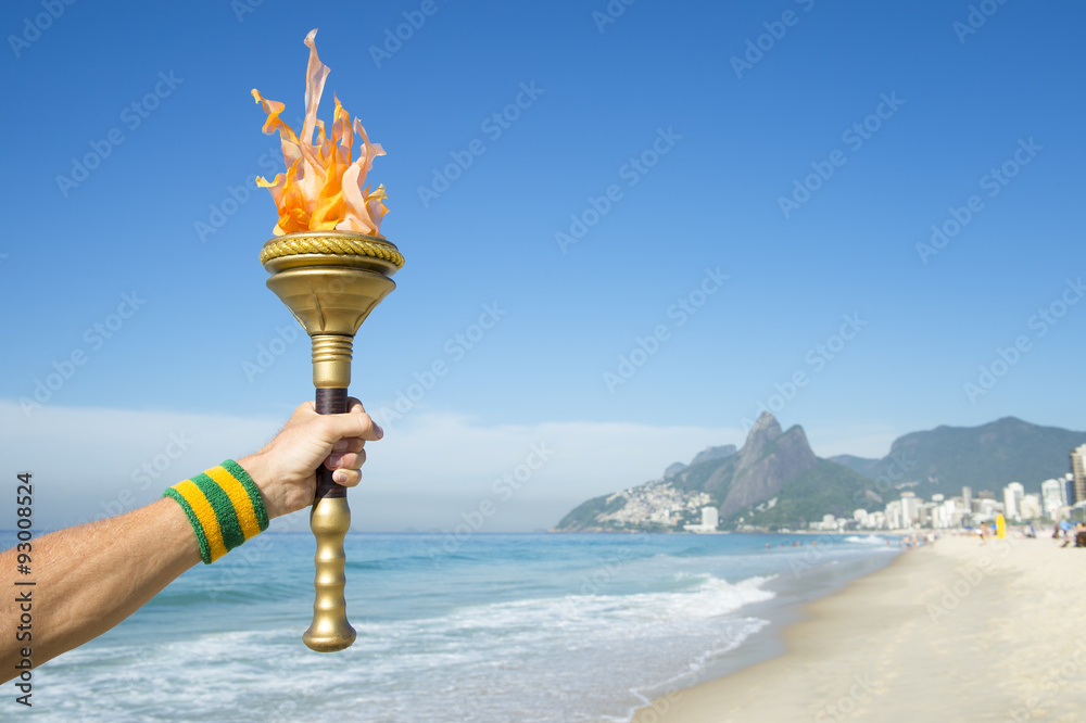 Φωτογραφία Hand of an athlete wearing Brazil colors sweatband holding sport torch on Ipanem